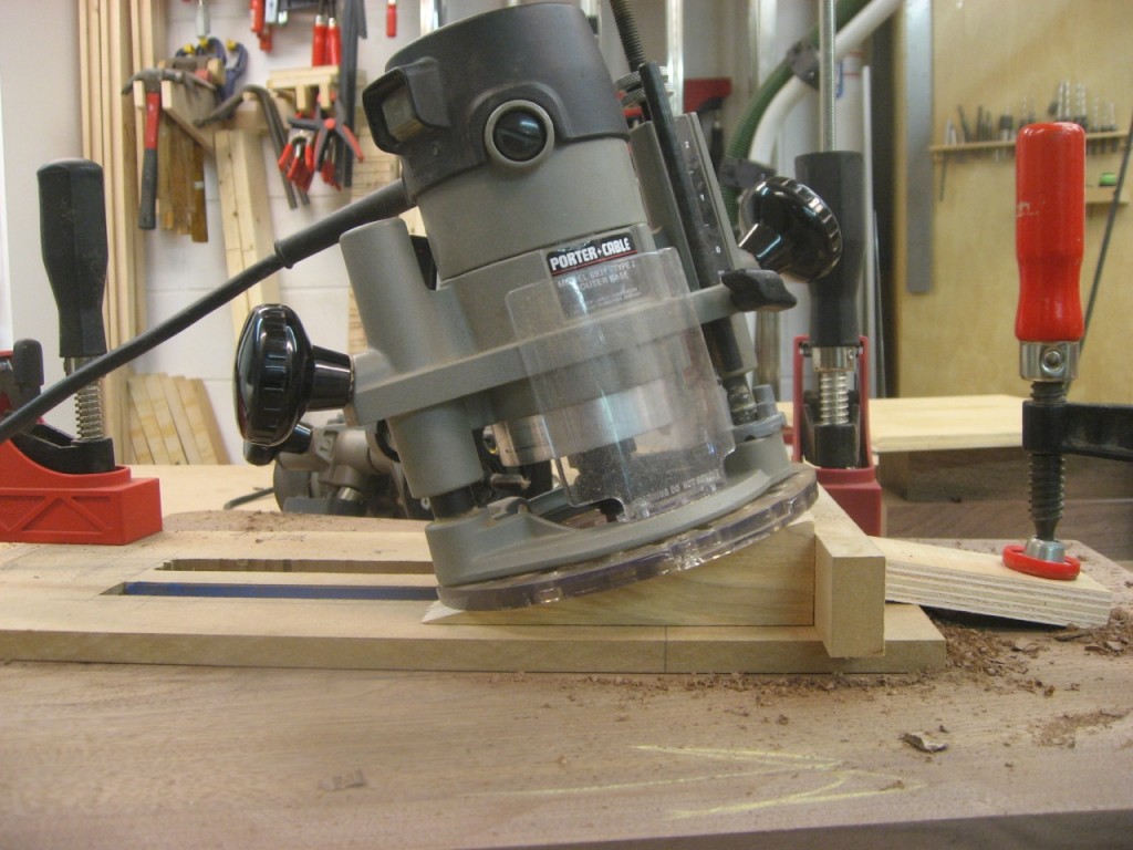 The router runs at an angle for the bit to remove waste at the bottom of the mortise