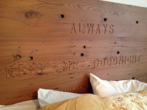 The 2x12 redwood boards that made the rails of our pre-Katrina Animal General Hospital sign were planed, sanded and glued up to make this simple, rustic headboard. The engraved phrase came from a Delta Airlines SkyMall catalogue advertising a needlework project. I wrote down the expression while on a flight to see our grandchildren, and kept it tacked to the shop wall for years before finding the right place to use it.
