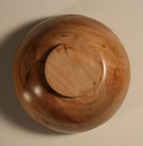 This shows the bottom of the natural edge cherry bowl where you can see six knots.